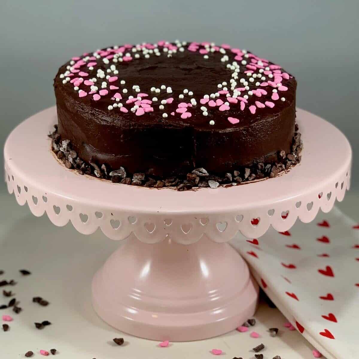 Whole port wine chocolate cake on a pink cake stand.