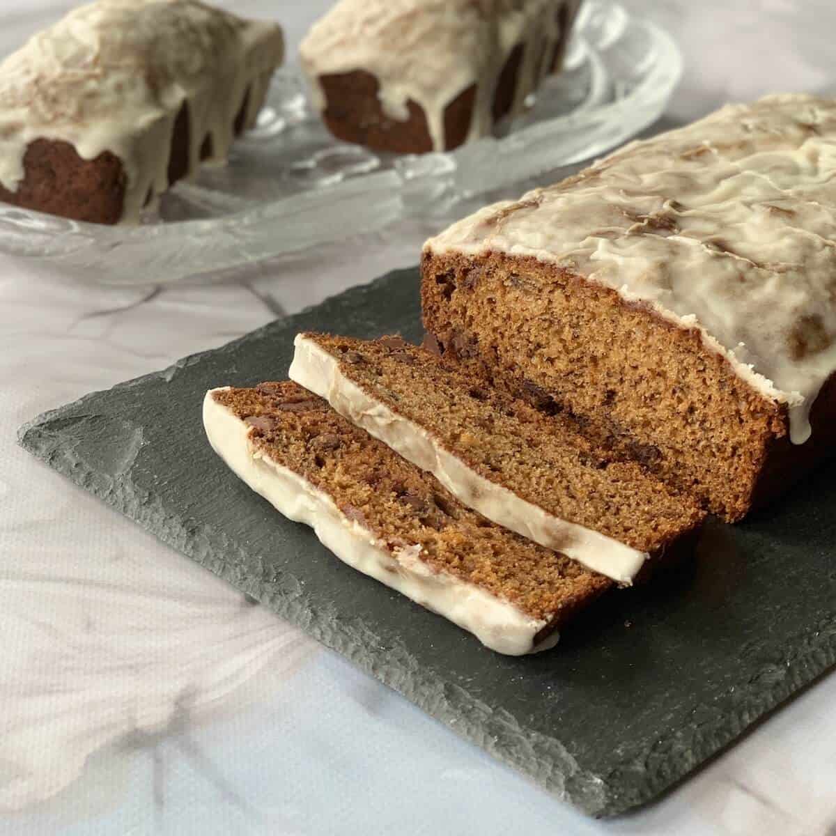 Sliced Sourdough Banana Bread loaf in foreground with whole small loaves in background.