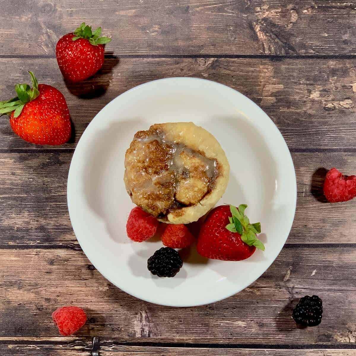 Cinnamon Rolls on a white plate with berries from overhead.