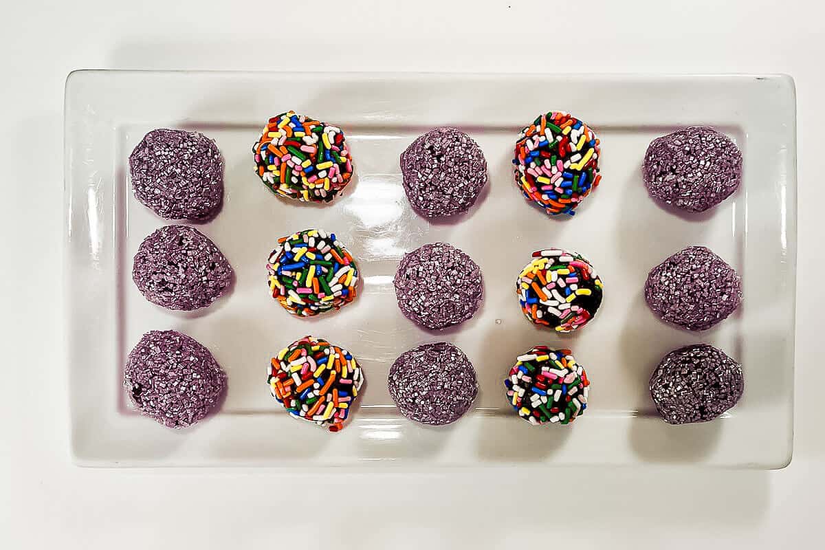 Rum balls with different topping on a white plate from overhead.