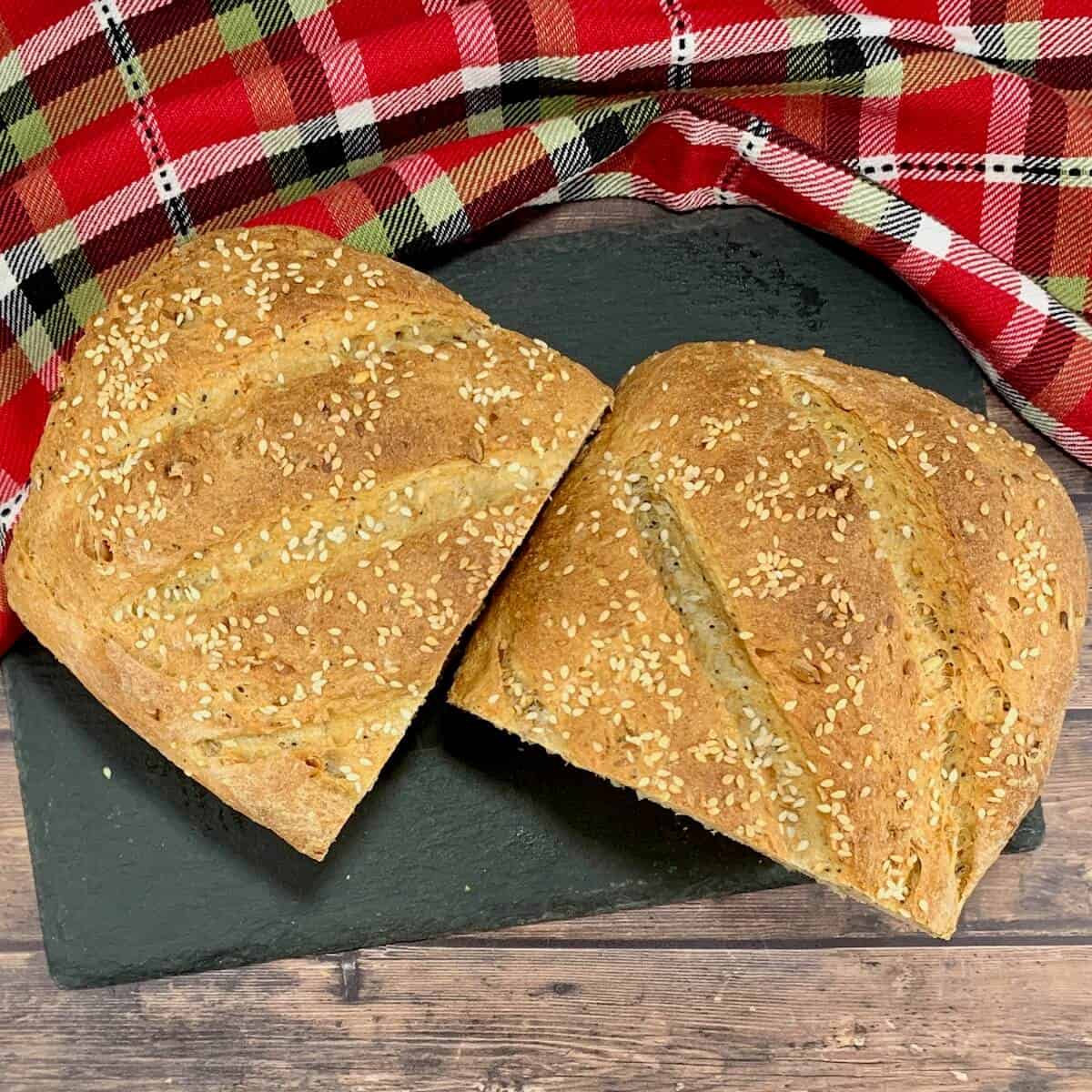 Halved Multigrain Sourdough Sandwich Bread loaf on slate from overhead.