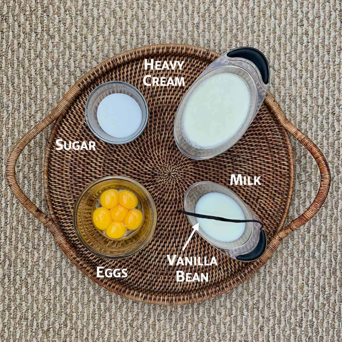 Creme Brulee ingredients portioned into glass bowls on wooden tray.