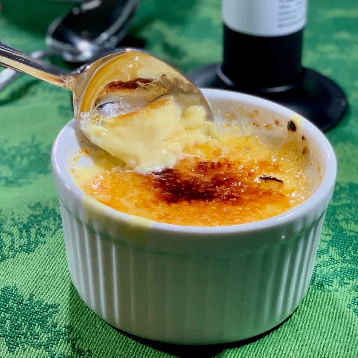 Creme Brulee on a green towel with a lifted spoon.