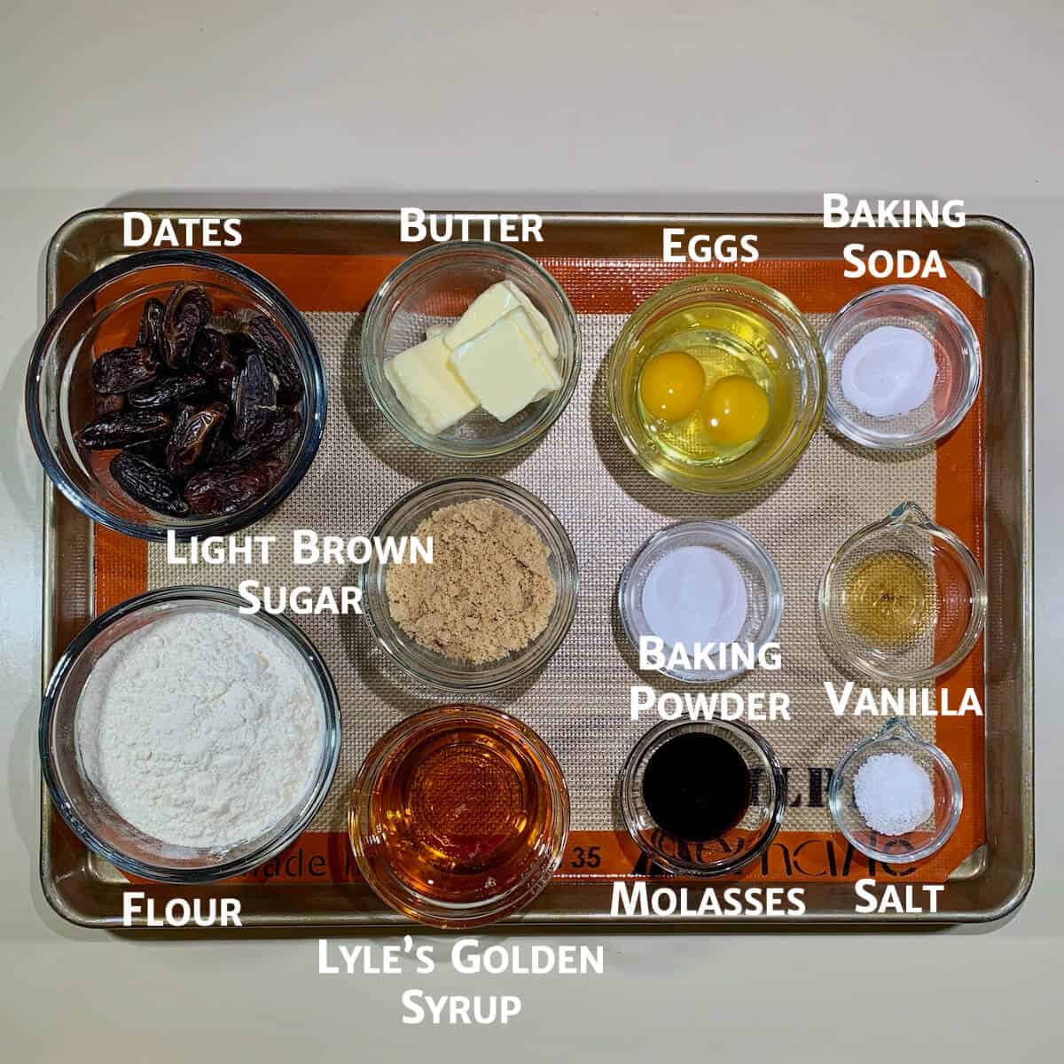 Sticky Toffee Pudding cake ingredients portioned in glass bowls on a baking pan.