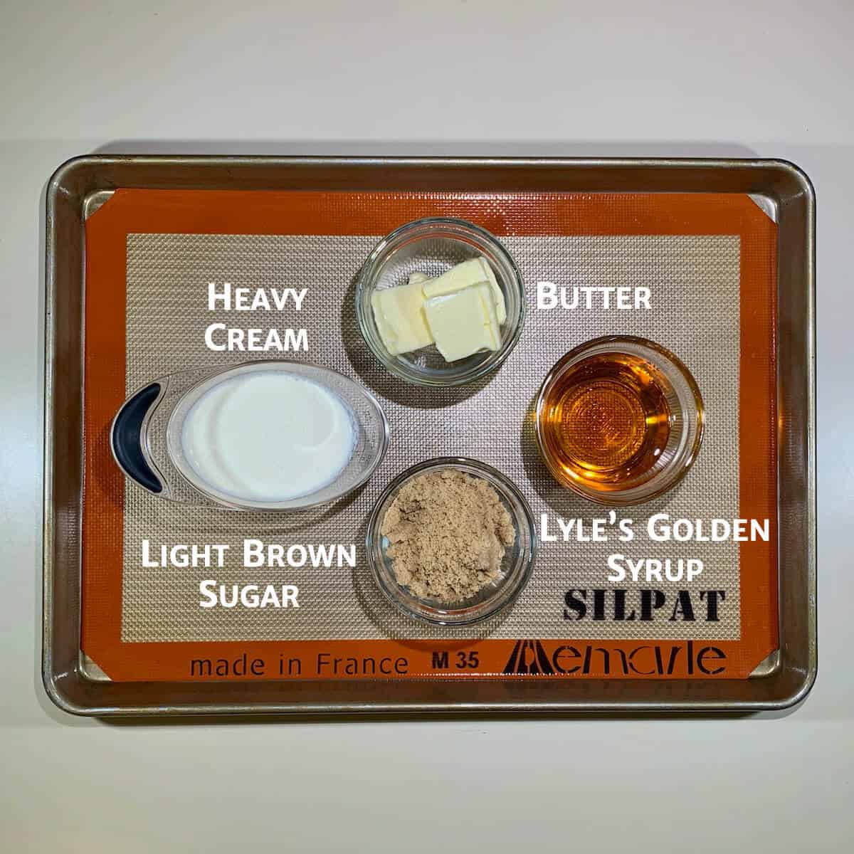 Toffee sauce ingredients portioned in glass bowls on a baking pan.