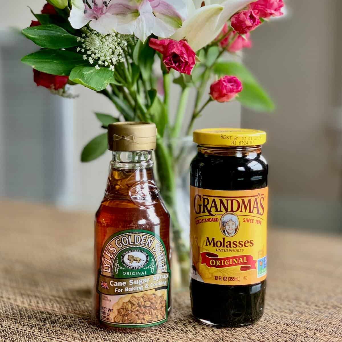 Lyle's Golden Syrup & Grandma's molasses on table with flowers.