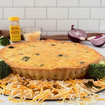 Chicken Broccoli Quiche on a gold base with cheese, seasonings, & red onion.