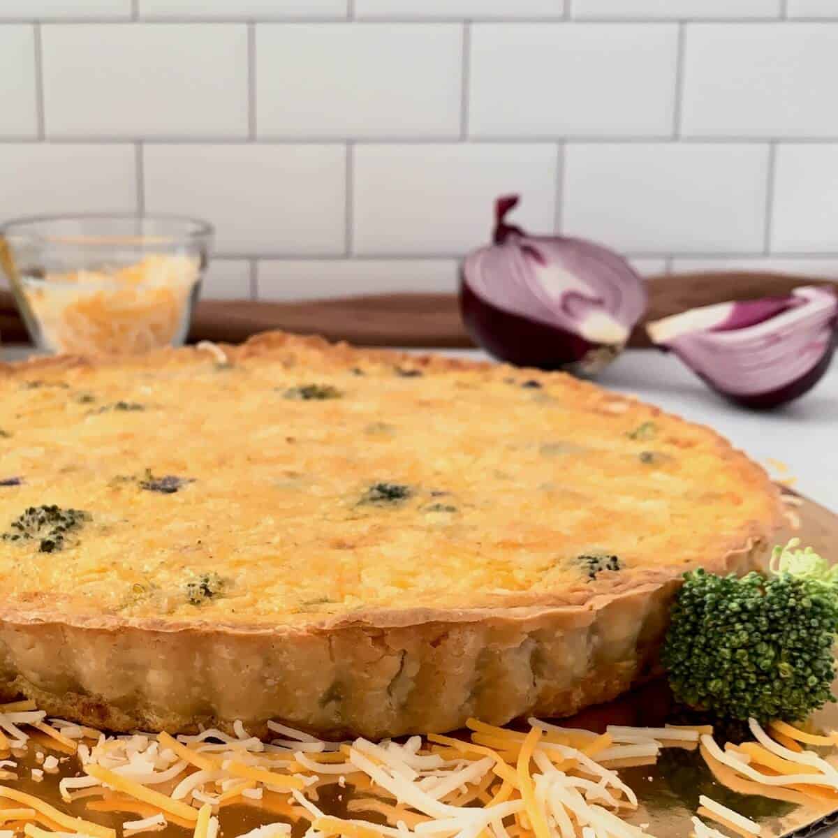 Chicken Broccoli Quiche on a gold base with cheese & red onion.