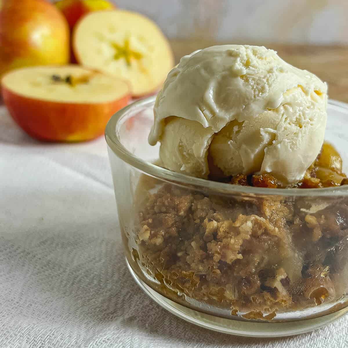 Apple Crisp on a grey-rimmed white plate with vanilla ice cream & caramel sauce on the side.