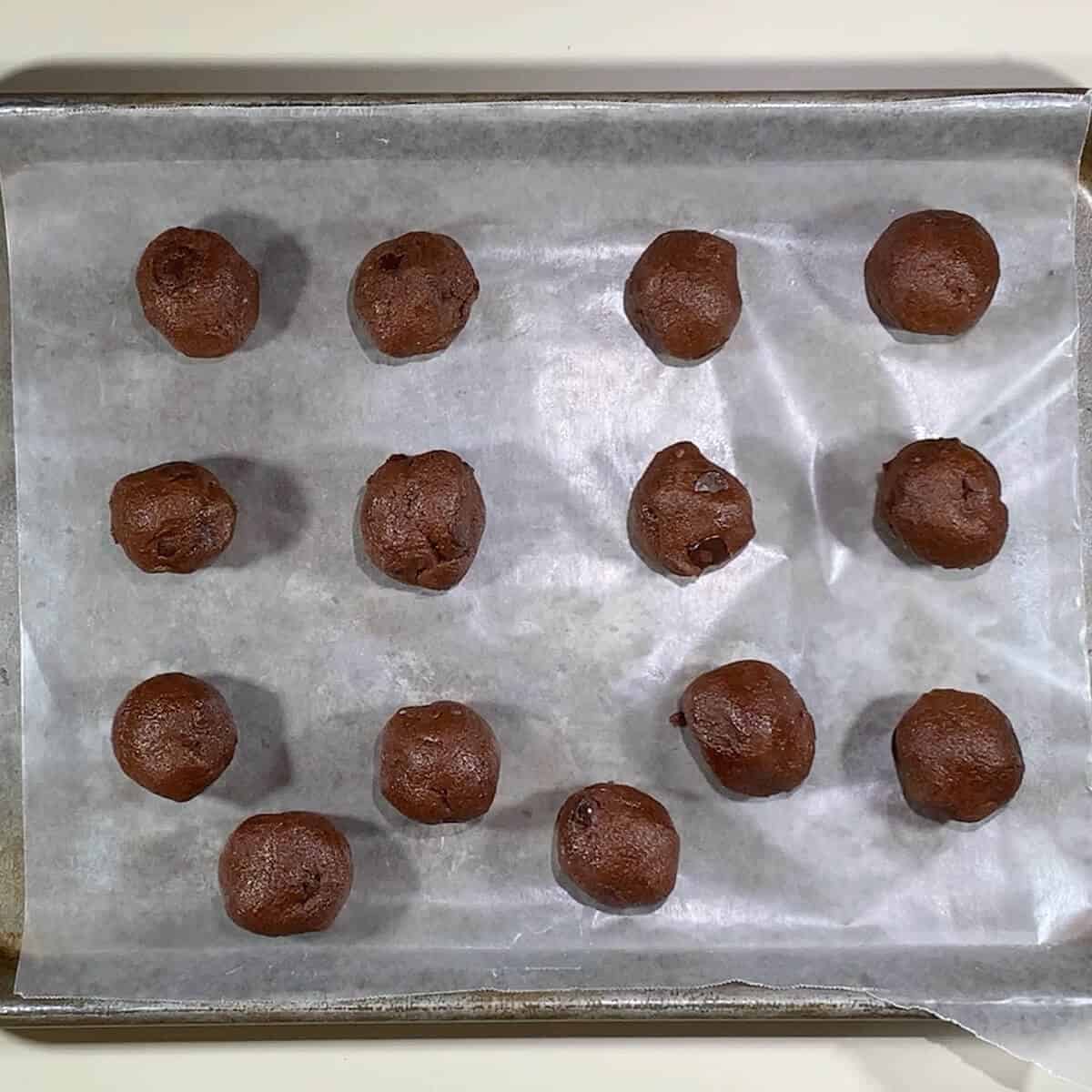 Chocolate Chocolate Chip cookie dough portions on wax paper lined tray for freezing.