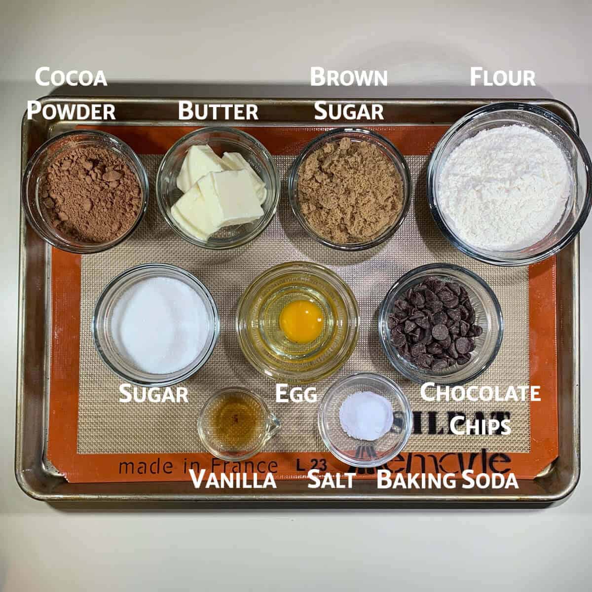 Chocolate Chocolate Chip cookies ingredients portioned in glass bowls on tray from overhead.