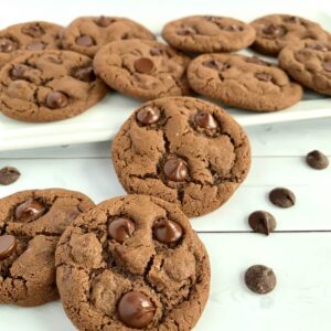 Chocolate Chocolate Chip cookies with white tray of cookies behind.