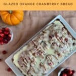 Glazed Orange Cranberry Bread on a white plate with pumpkins & cranberries from overhead Pinterest banner.