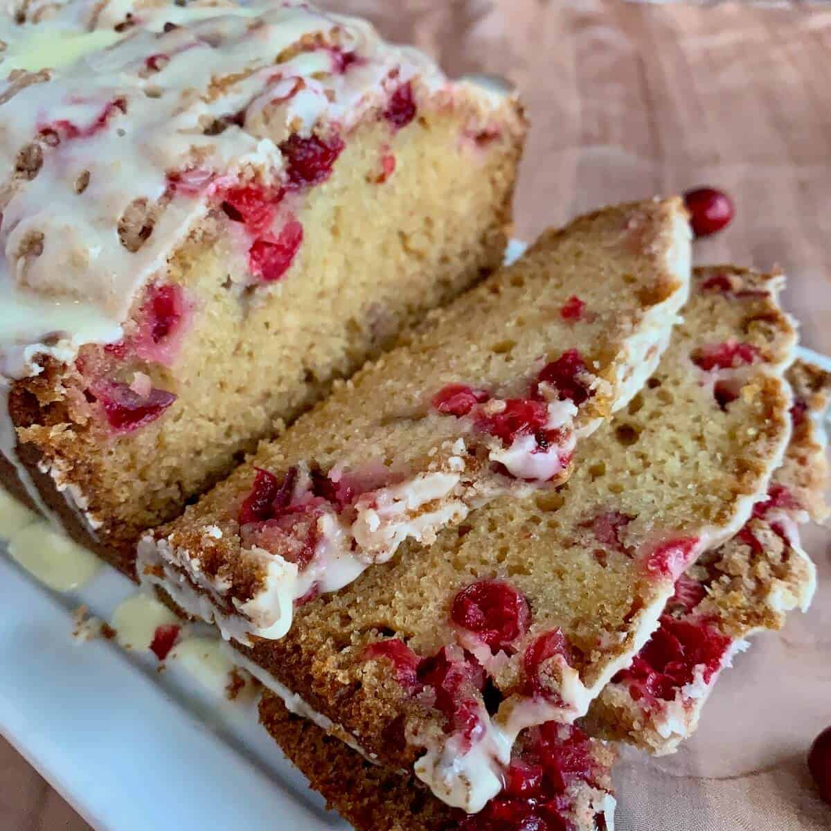 Glazed Orange Cranberry Bread sliced on a white plate.