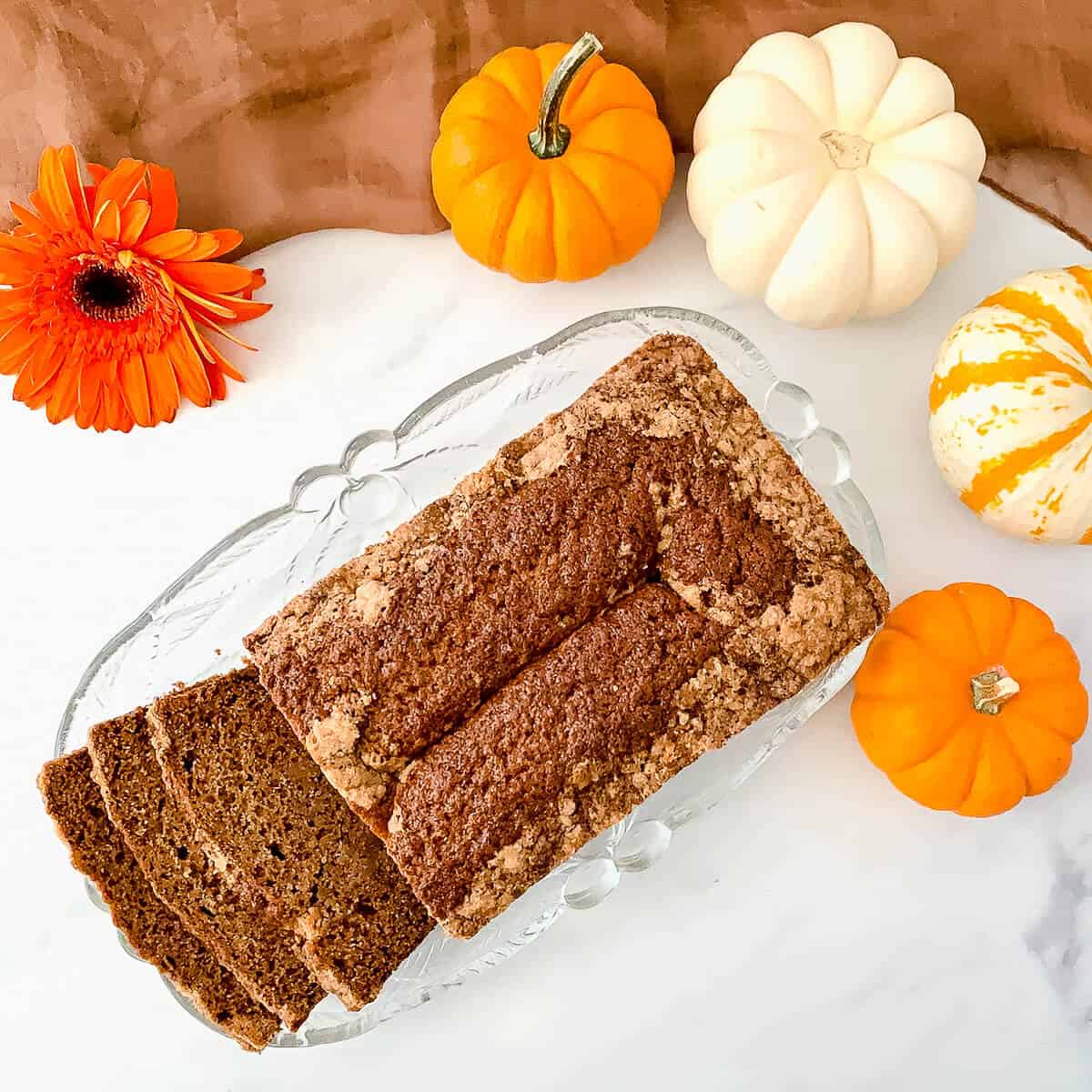 Sourdough Spice Cake sliced on glass plate with pumpkins. from overhead.