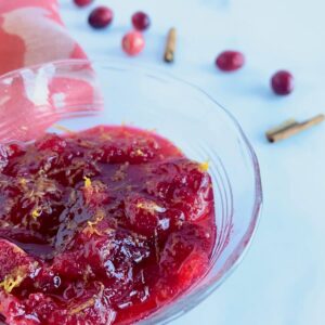 Orange Cranberry Sauce in a glass bowl with ingredients.