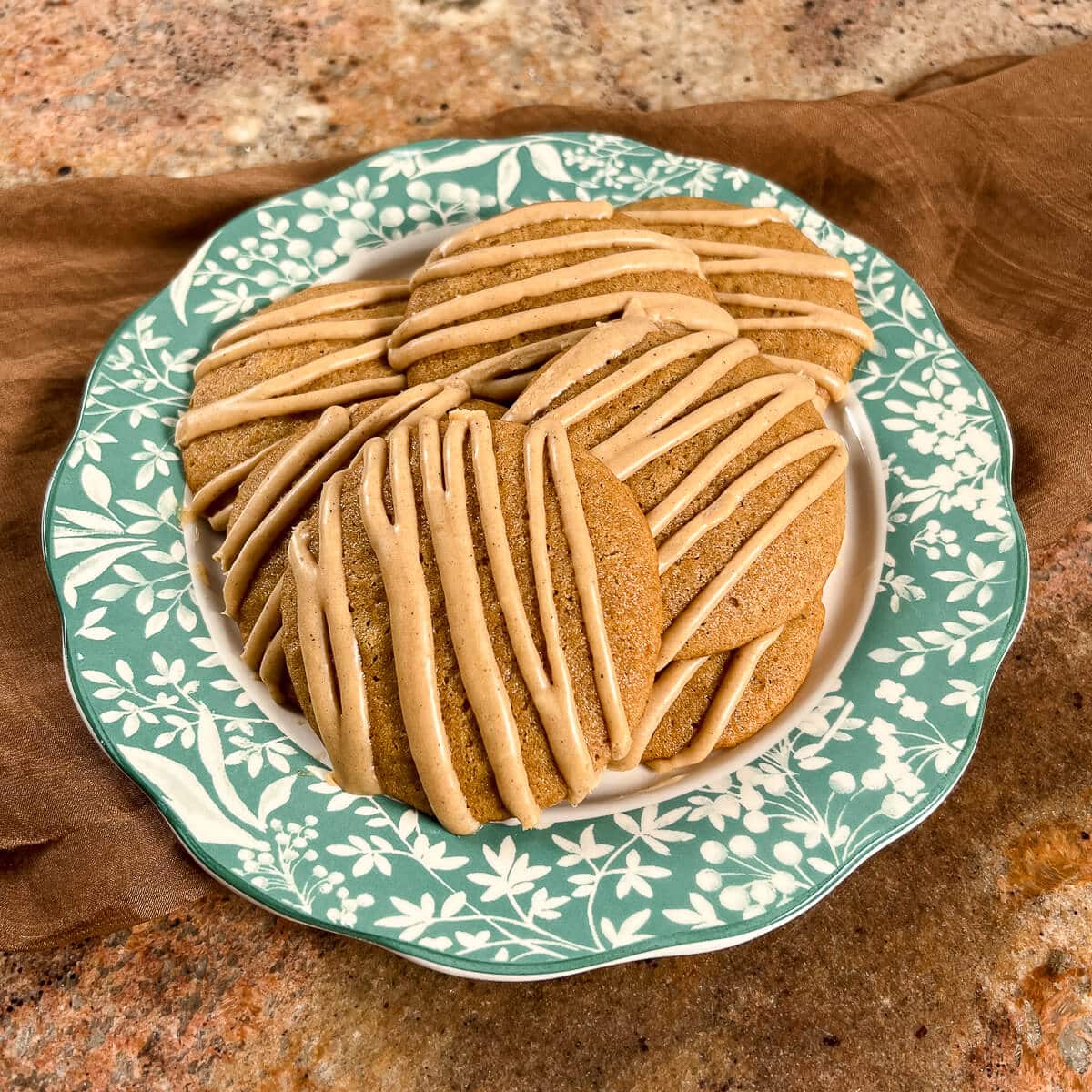 Apple spice cookies stacked on plate with a green flowered edge.