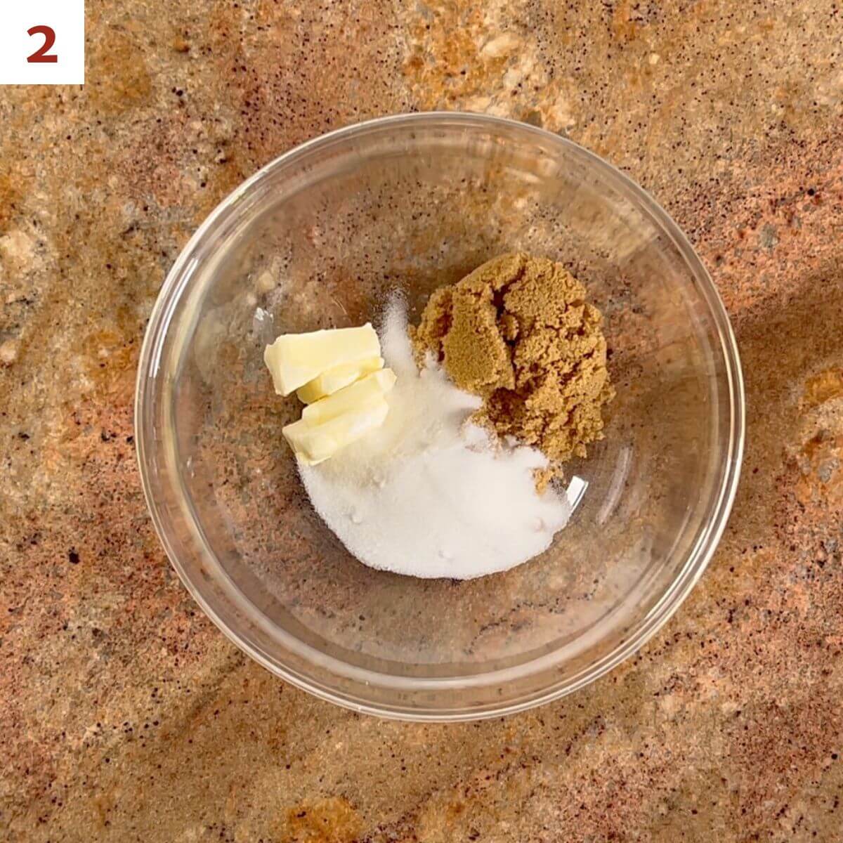 Sugar, brown sugar, and butter in a glass bowl from overhead.