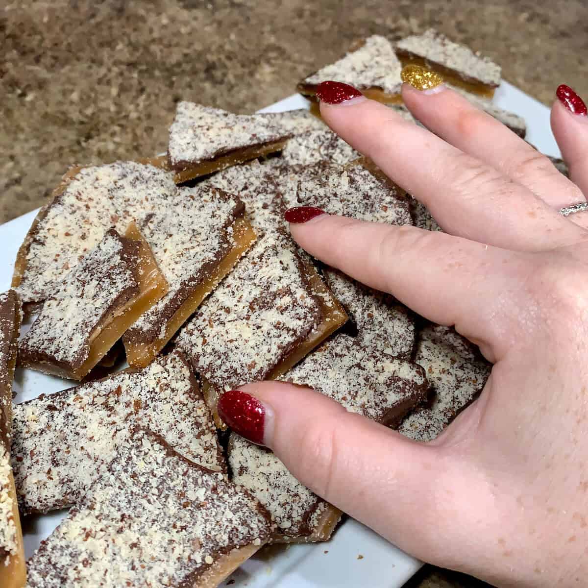 Taking a piece of English Toffee laid out on a white plate.