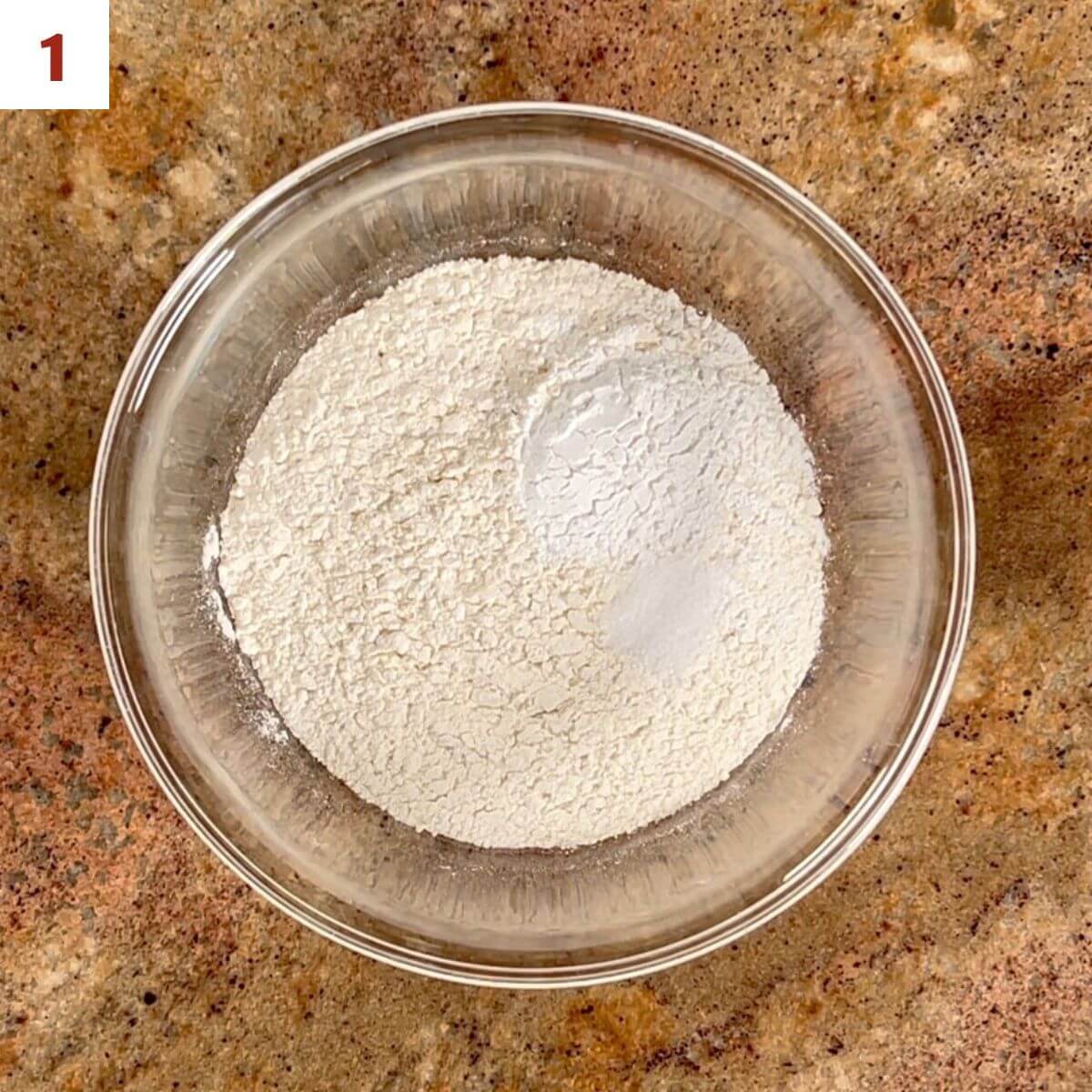 Flour, baking powder, and salt in a glass bowl from overhead.