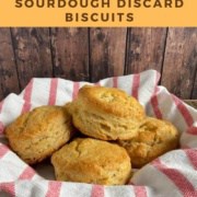 Biscuits stacked on a red & white striped towel nestled in a bowl Pinterest banner.