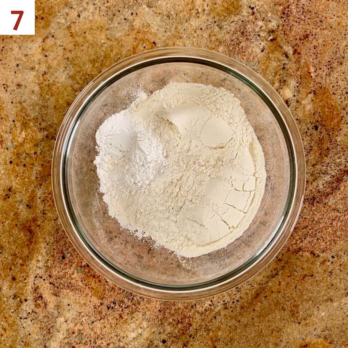 Flour, baking powder, and salt in a glass bowl from overhead.