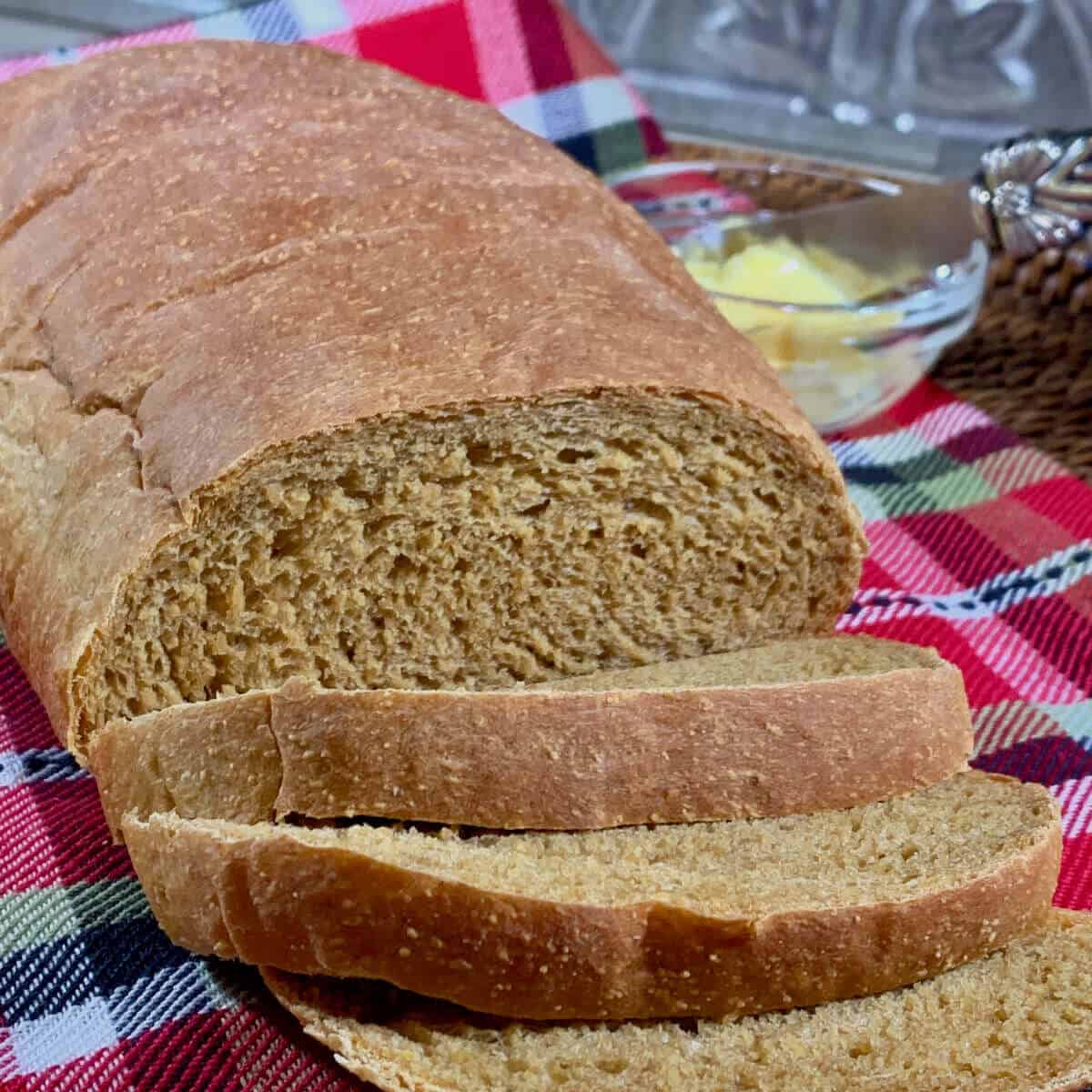 Sliced Colonial Bread on plaid towel with butter.