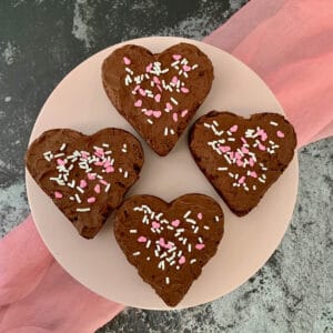 Four heart shaped Fudge Brownies on cake stand from overhead.