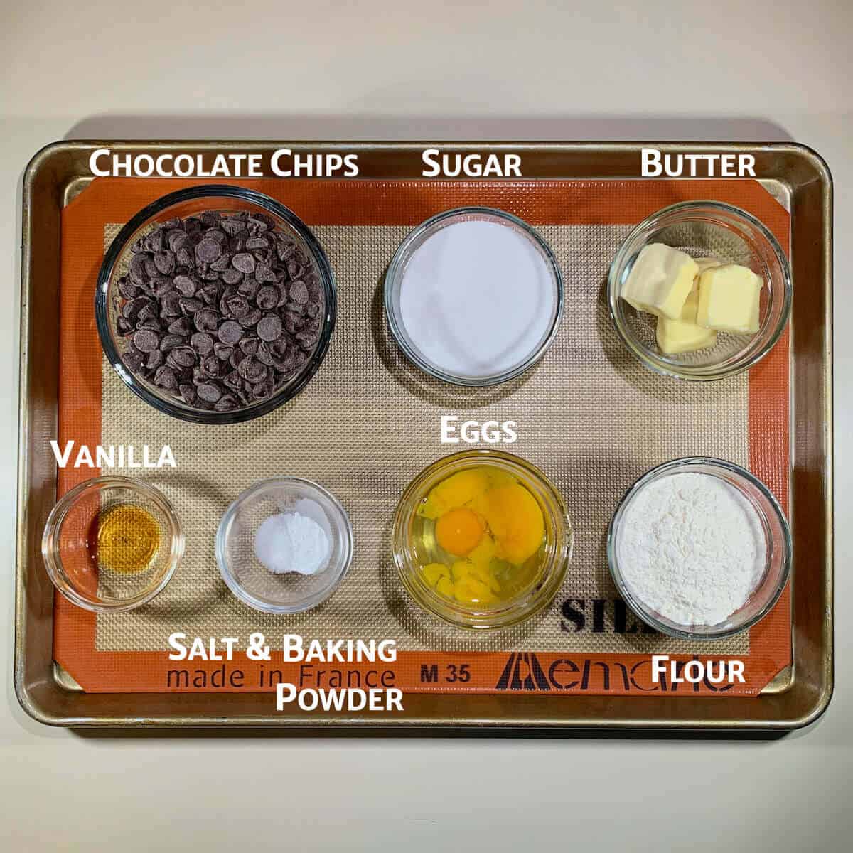 Fudge brownies ingredients portioned into glass bowls on tray from overhead.