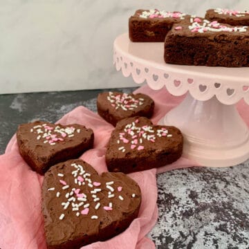Heart shaped Fudge Brownies on pink scarf and cake stand.