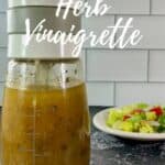 Bottle of herb vinaigrette in foreground and plated salad in background Pinterest banner.
