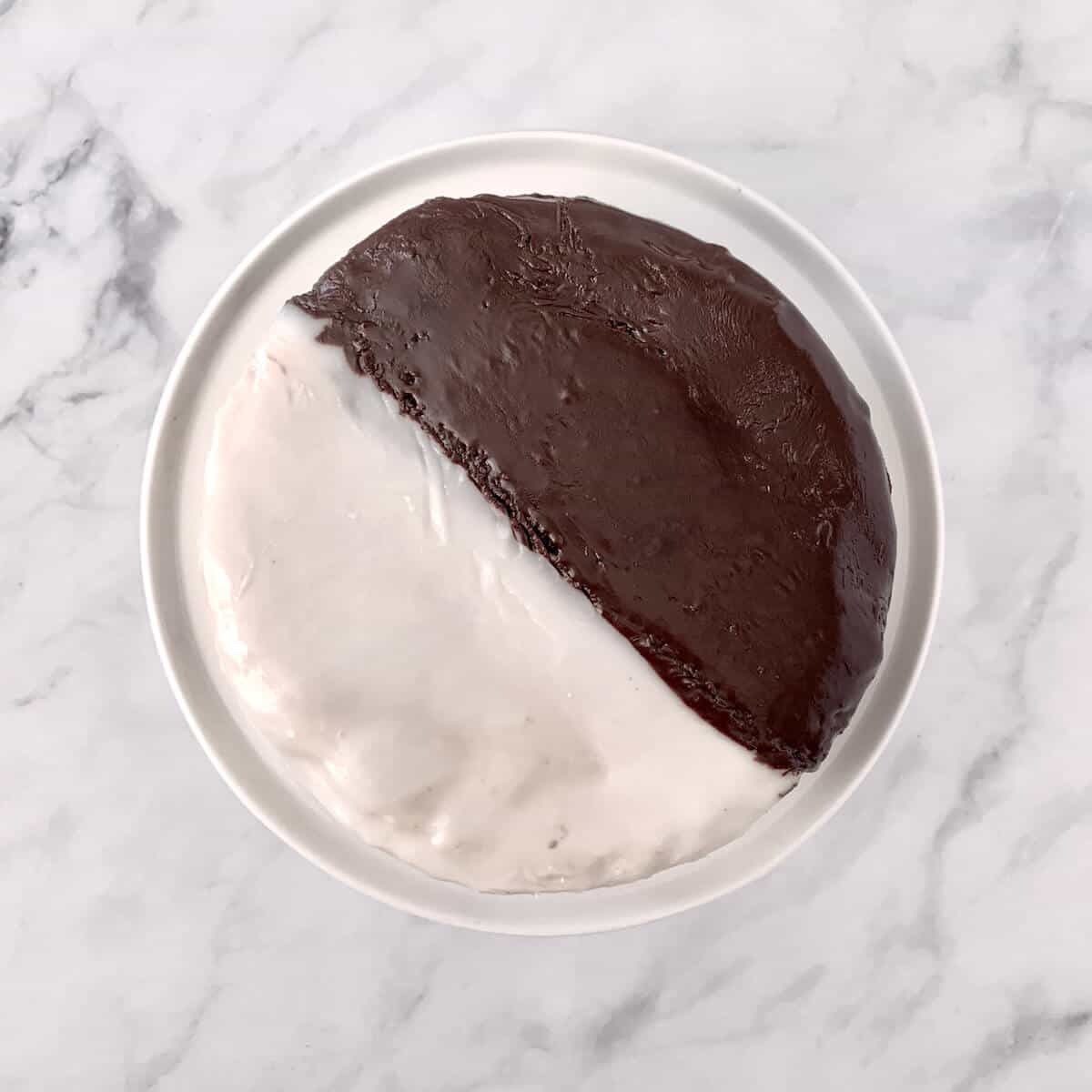 Whole Black & White Cookie Cake on a white cake stand from overhead.