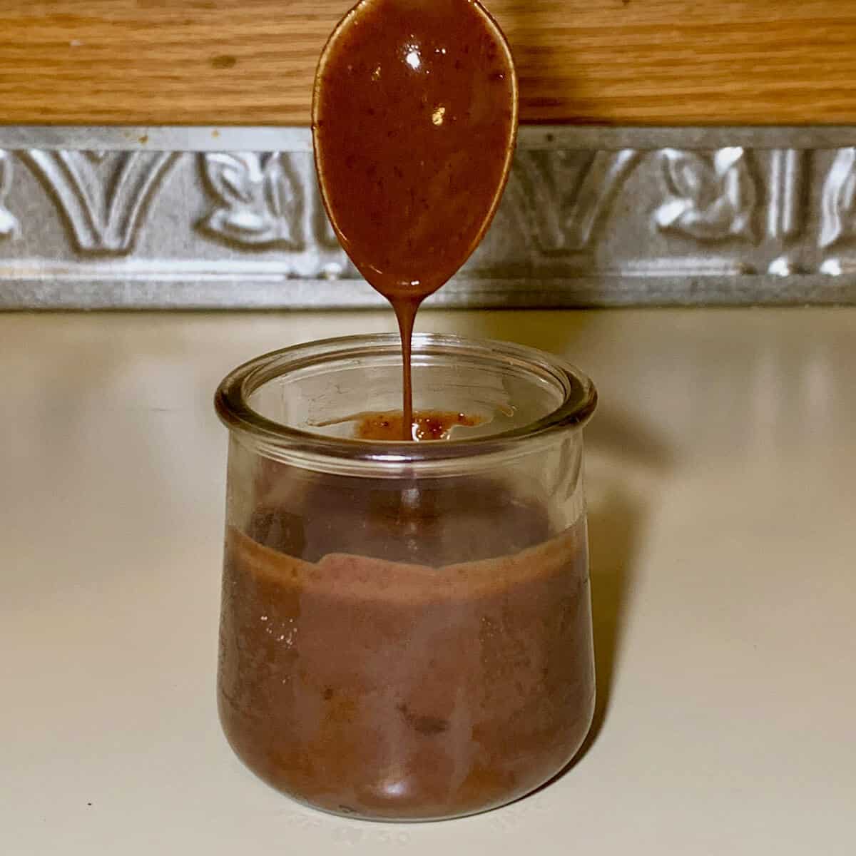 Thin chocolate ganache dripping into jar.