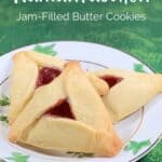 Raspberry Hamantaschen cookies stacked on a white plate with green trim on a green background Pinterest banner.