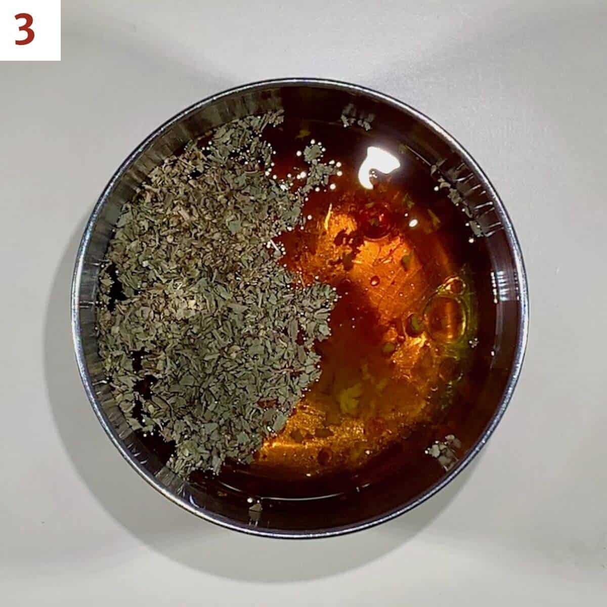 Adding oil to vinaigrette in a metal bowl.