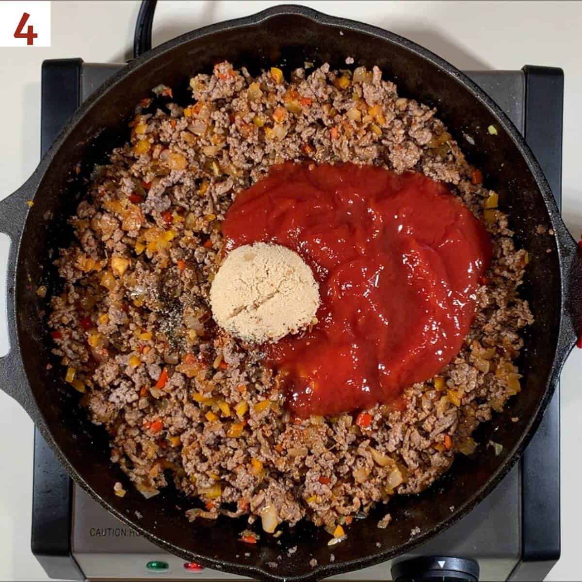 Adding ketchup & spices to sloppy joe filling.