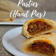 Sloppy Joes Pasties on a white plate sliced open with 2 stacked in background Pinterest banner.