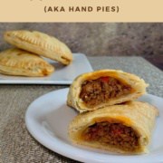 Sloppy Joes Pasties on a white plate sliced open with 2 stacked in background Pinterest banner.