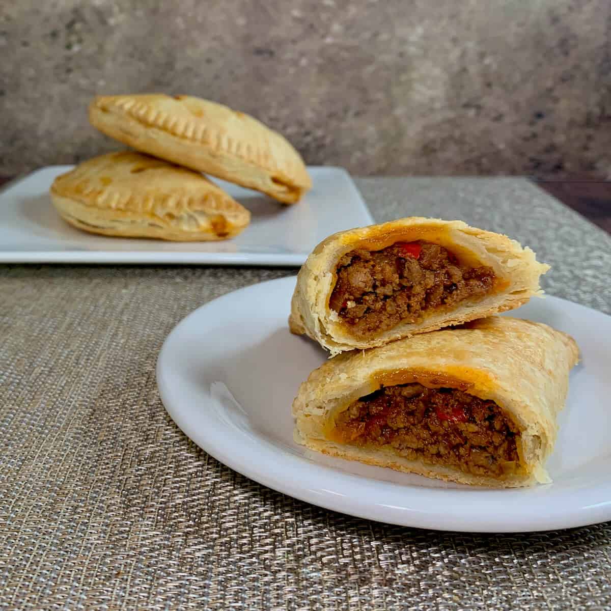 Sloppy Joes Pasties on a white plate sliced open with 2 stacked in background Pinterest banner.