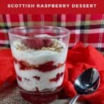 Glass filled with Cranachan layers next to a spoon on a red & plaid scarf Pinterest banner.