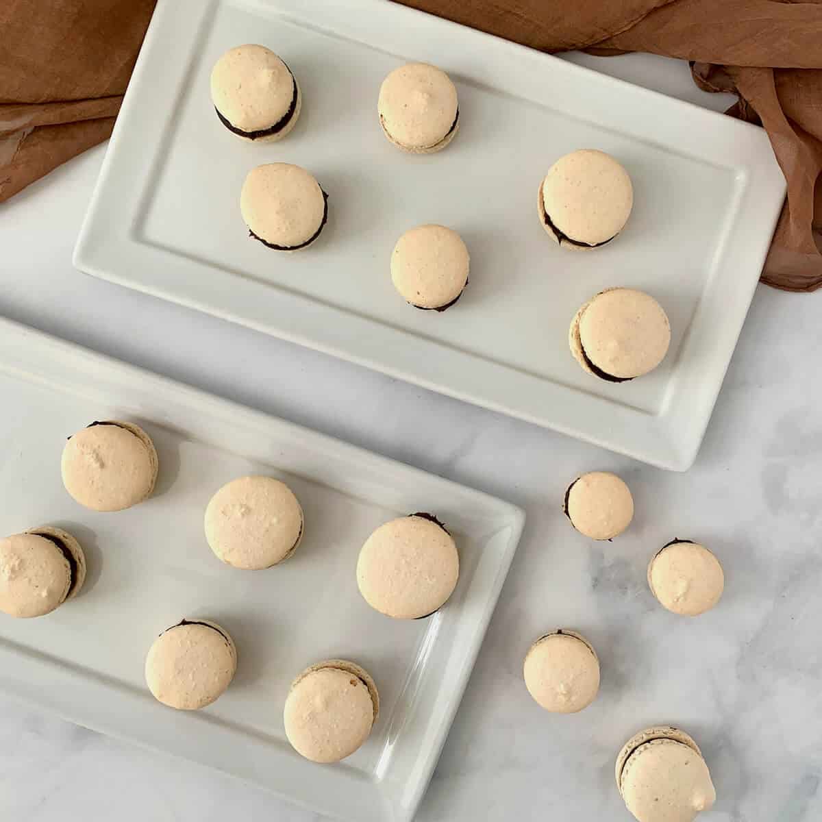 Italian Meringue Macarons plated on 2 white plates from overhead.