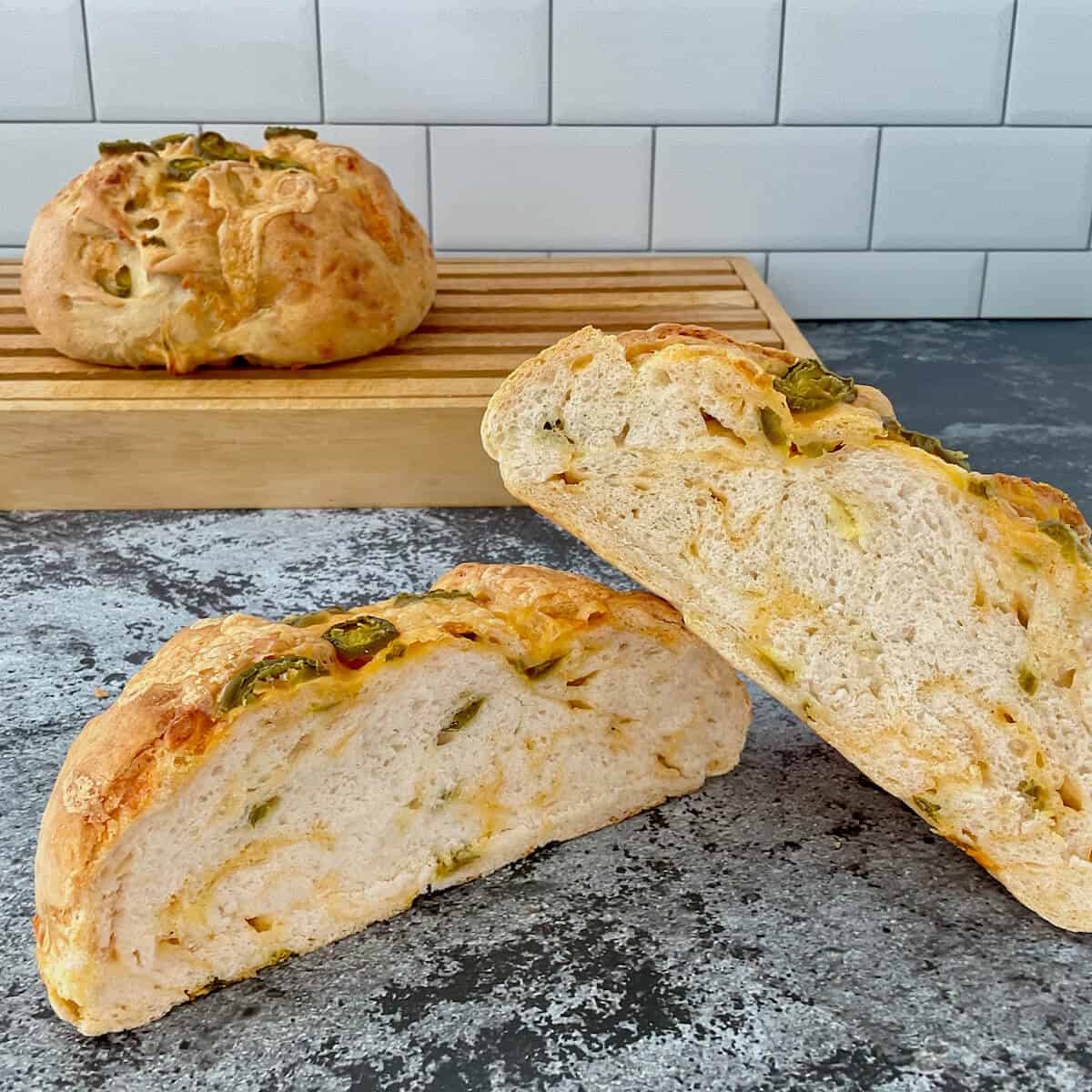 Sourdough Jalapeño Cheddar Bread sliced open closeup with loaf behind on cutting board.