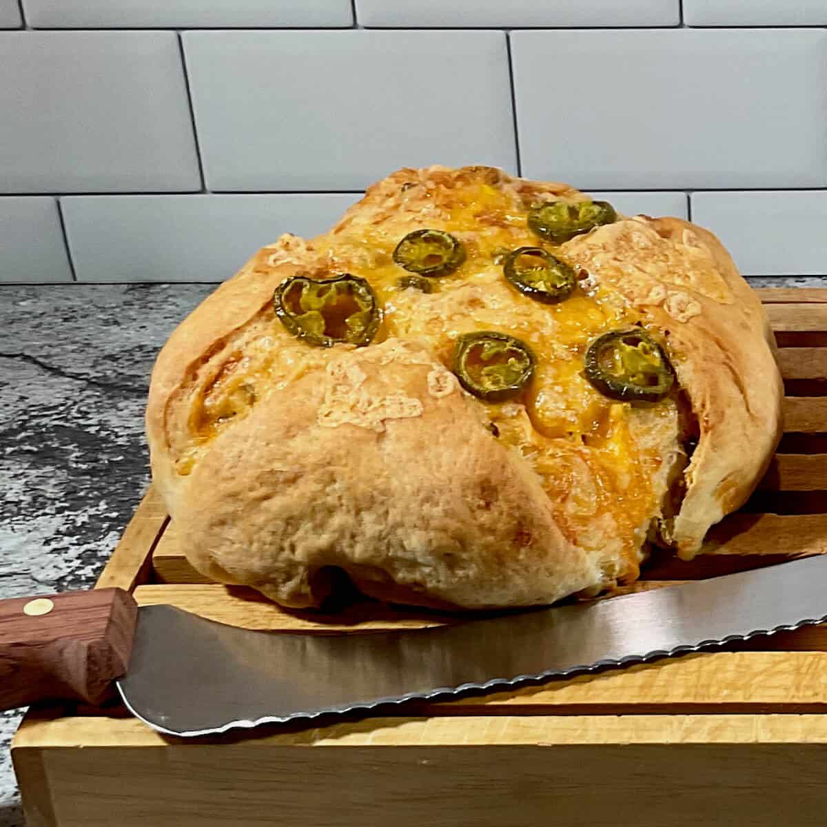 Sourdough Jalapeño Cheddar Bread on a cutting board with a knife.