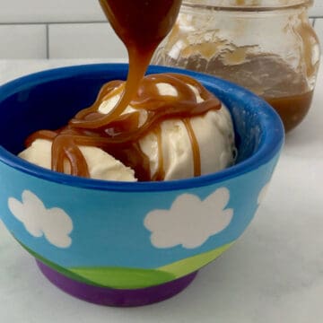 Pouring butterscotch sauce on vanilla ice cream.