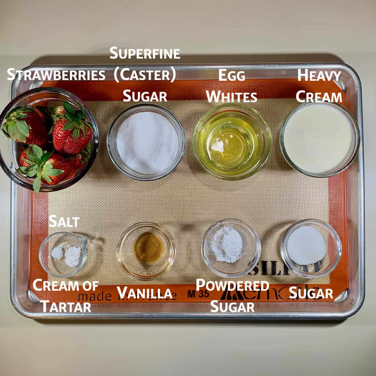 ingredients for Eton Mess portioned into glass bowls on a baking pan.