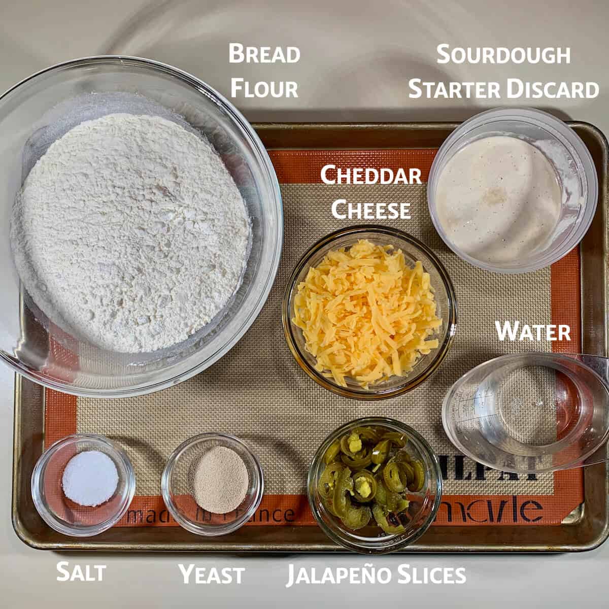 Sourdough Jalapeño Cheddar Bread ingredients in glass bowls on tray from overhead.