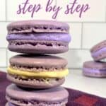 French Macarons with purple buttercream & lemon curd stacked on a purple towel with more in background.