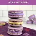 French Macarons with purple buttercream & lemon curd stacked on a purple towel with more in background.