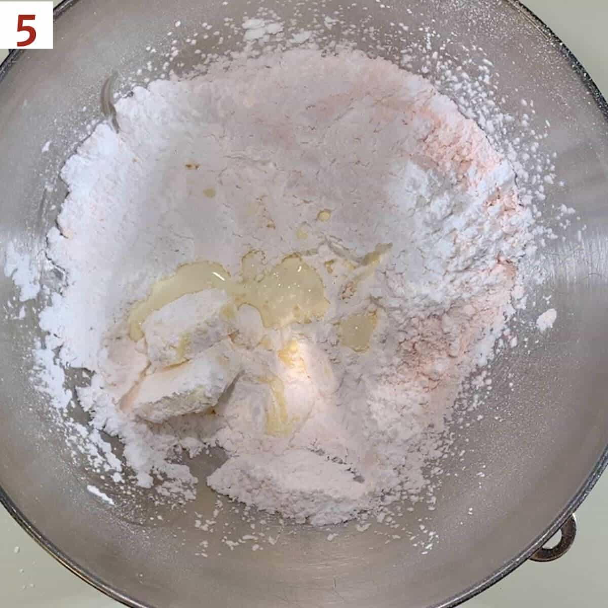Powdered sugar, butter, custard powder, and heavy cream in a metal mixing bowl.
