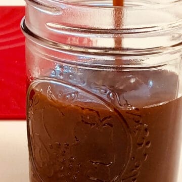 Caramel sauce being poured into a mason jar.